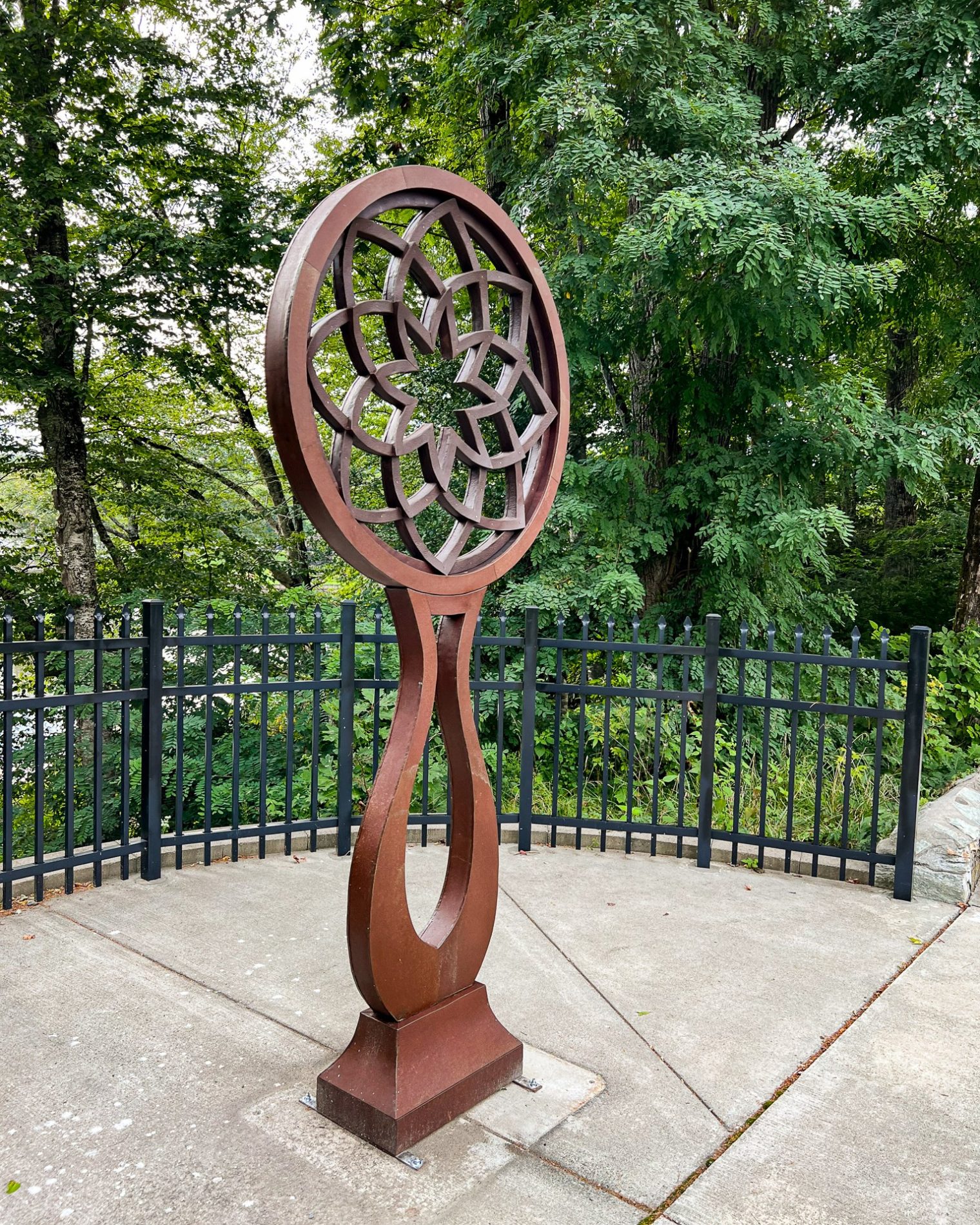 sculpture with rusted patina, showcasing the pattern of a lotus blossom on an open pedestal