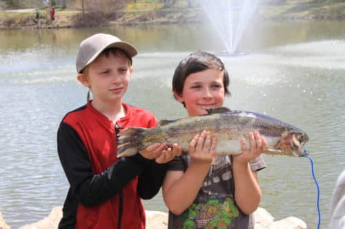 Trout Derby Event featuring two young brochures holding a large fish